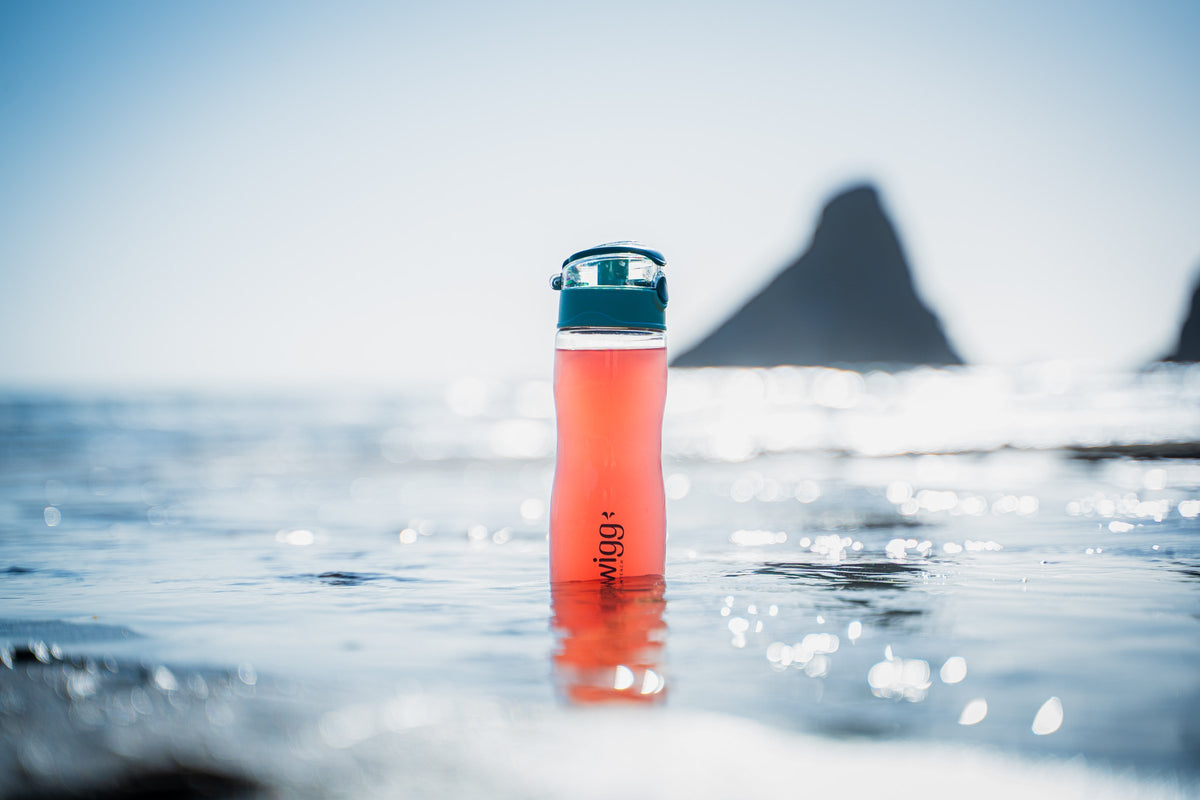 An orange Swigg bottle photographed on the Oregon coast