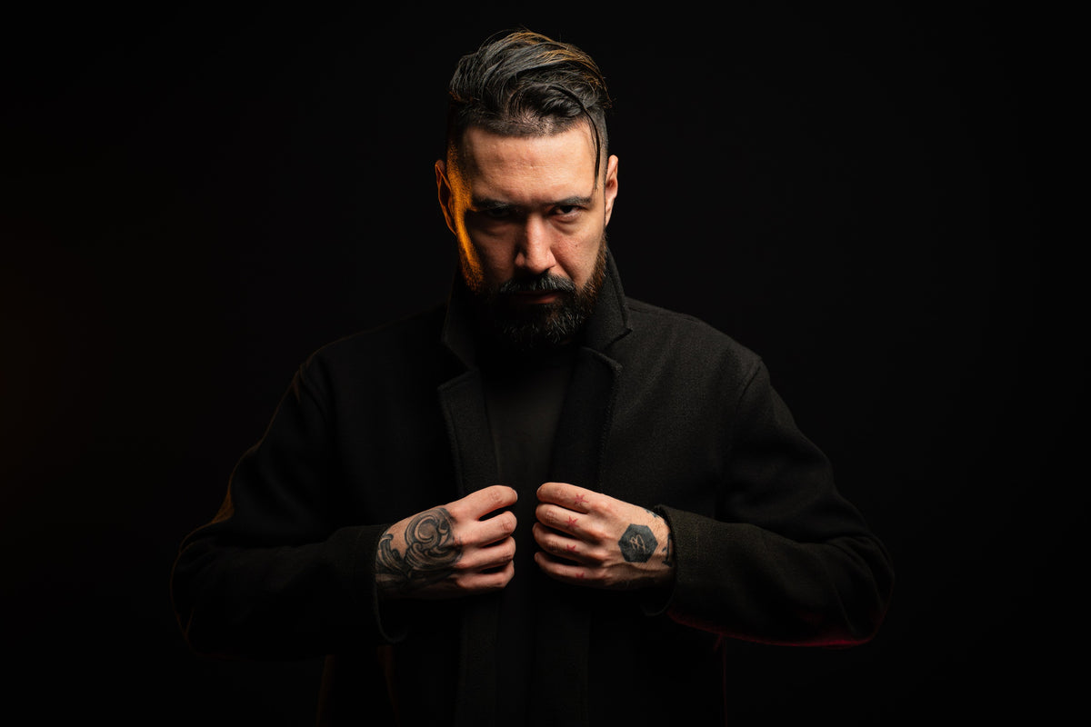 Studio portrait of a man in a black coat against a dark background