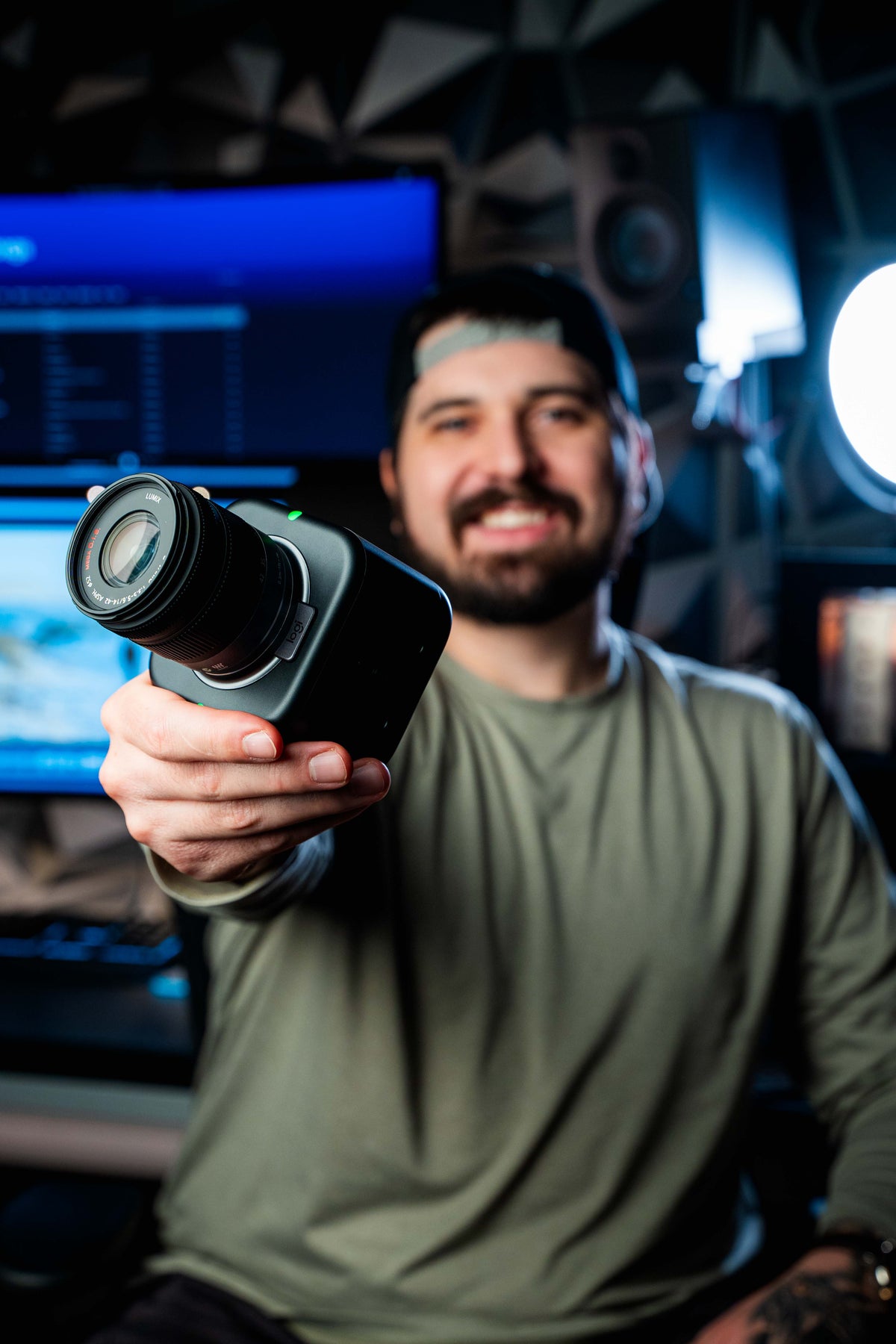 Tyler holding a Logitech camera in his editing studio