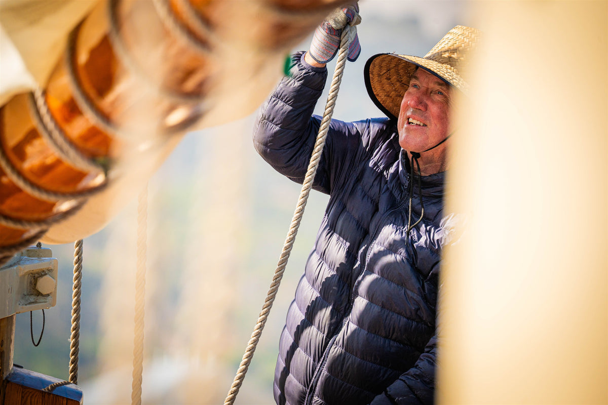 Crew member handling a rope framed by sailboat rigging