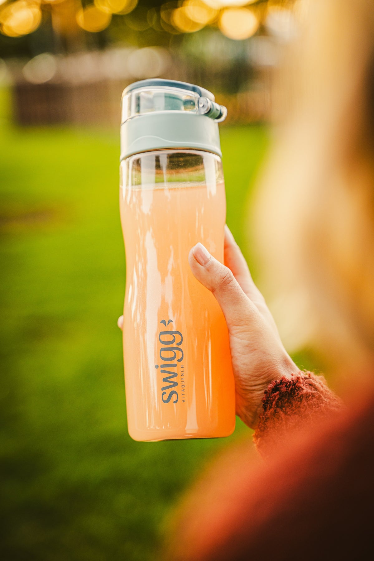 Orange Swigg bottle held upright in warm outdoor light