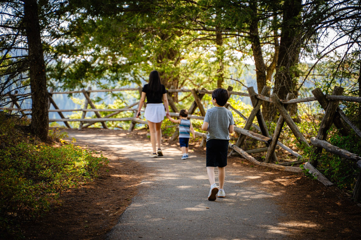 Family walking along a wooded path during a visit to Mesa Falls in Idaho