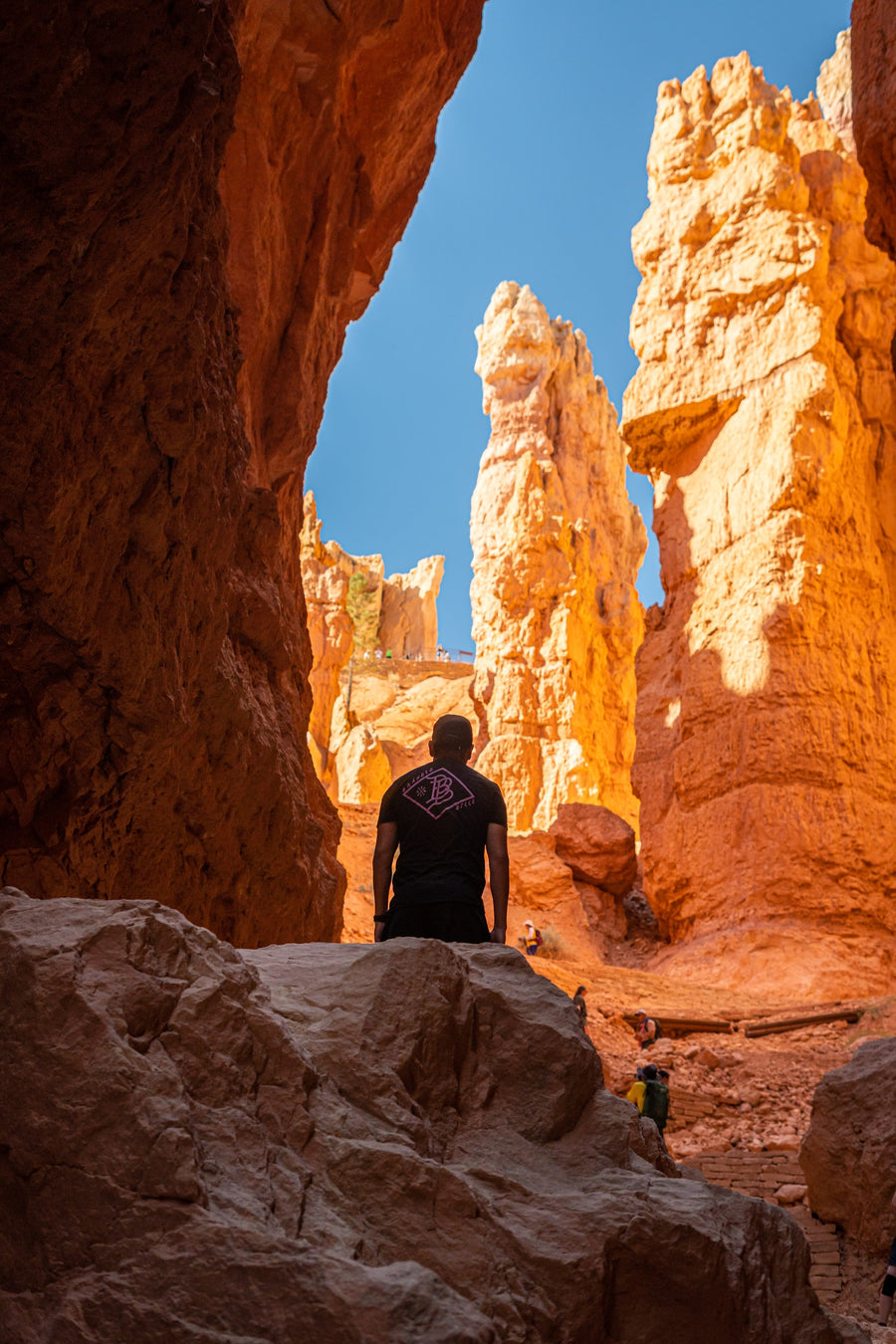 A person on a trail between tall orange rock walls and hoodoos in Bryce Canyon National Park
